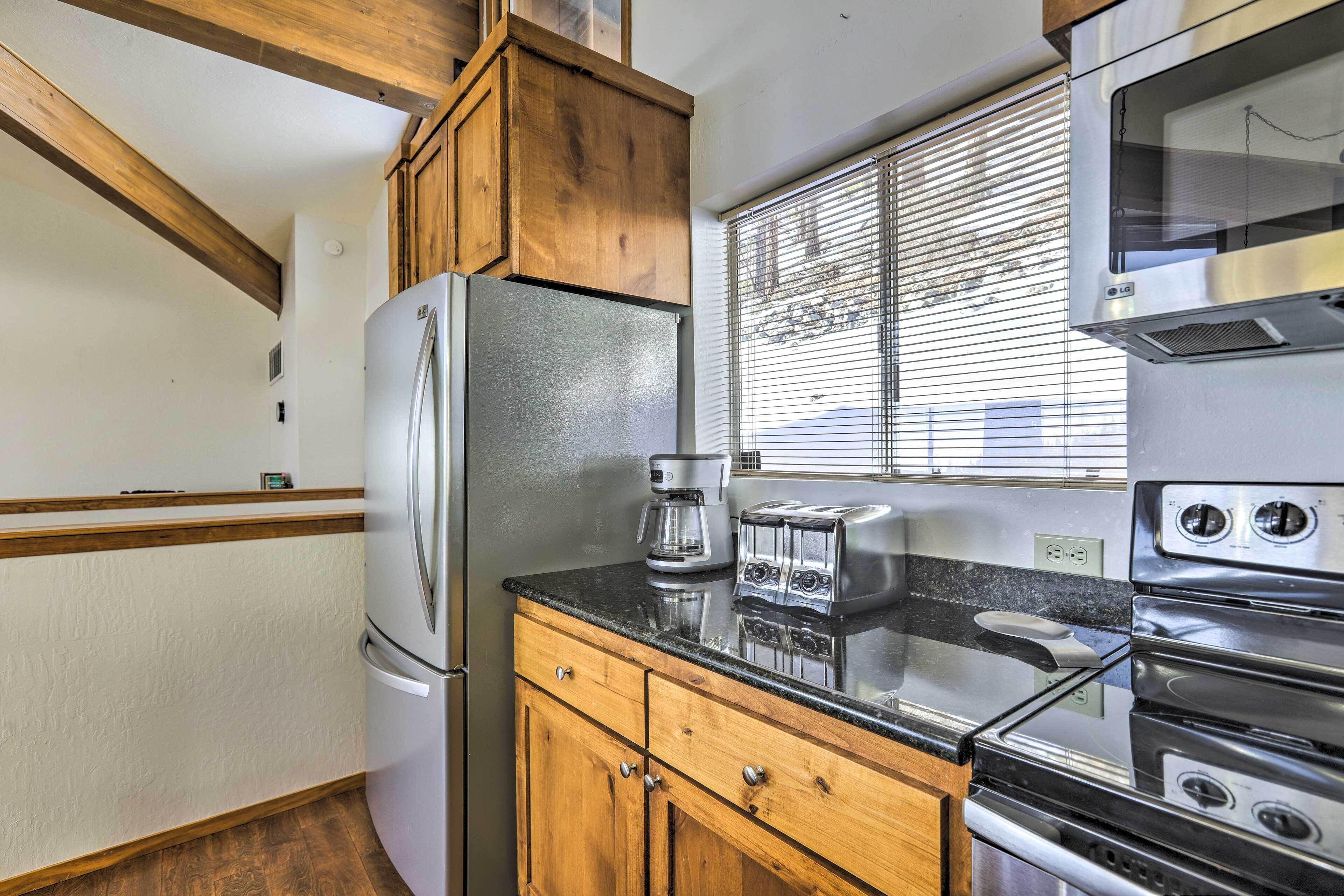 Una cocina compacta equipada con refrigerador, tostadora, cafetera y horno.