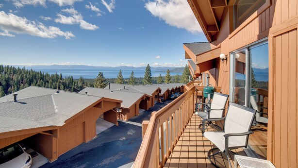 Une terrasse en bois avec des sièges d’extérieur, une vue sur les montagnes et une grande fenêtre donnant sur le paysage.