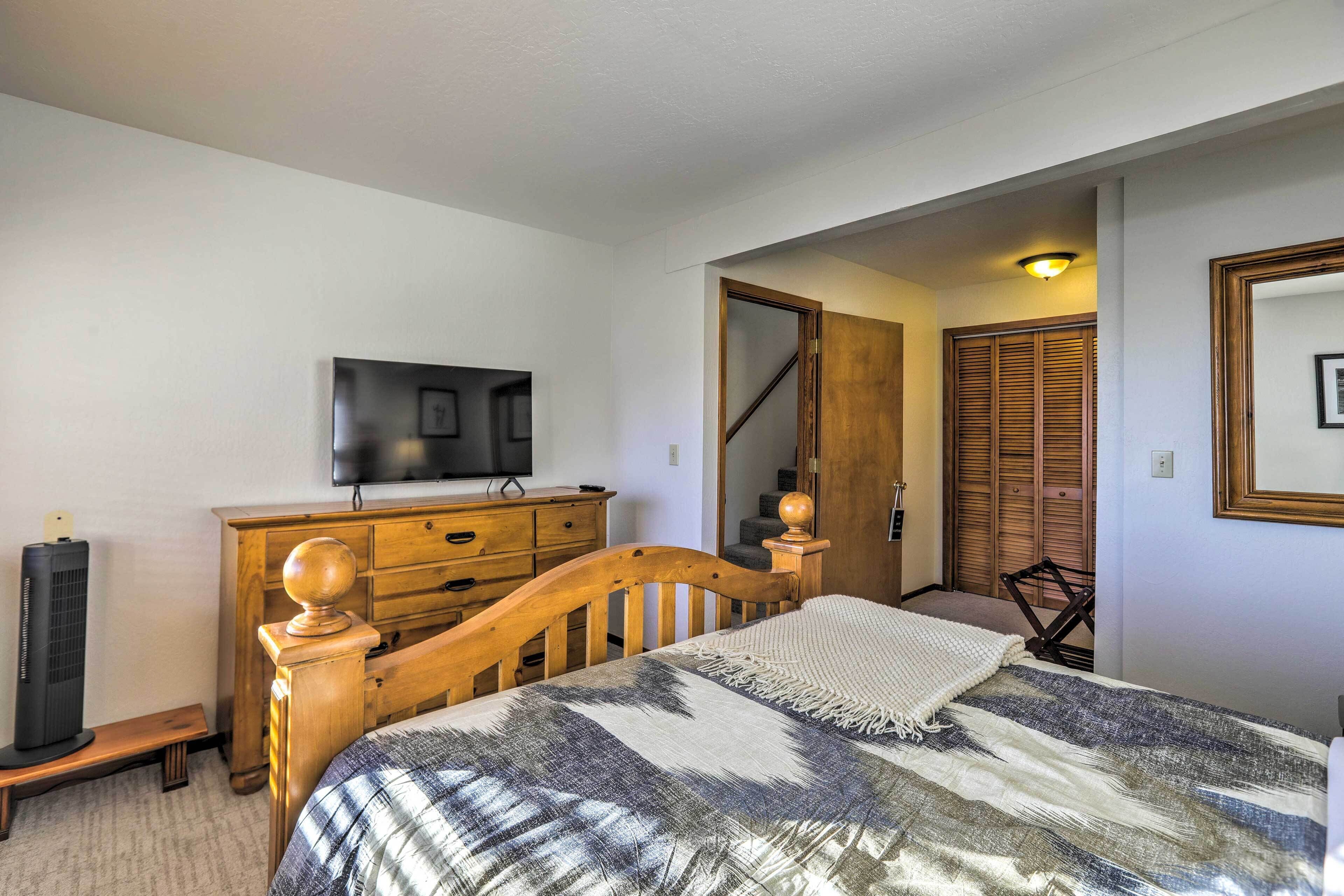 Una camera da letto con un letto di legno, una cassettiera, un televisore montato a parete e uno specchio.