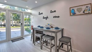 Una cocina moderna con un ventanal que da a un balcón, una mesa con taburetes y una pared con frases motivacionales.