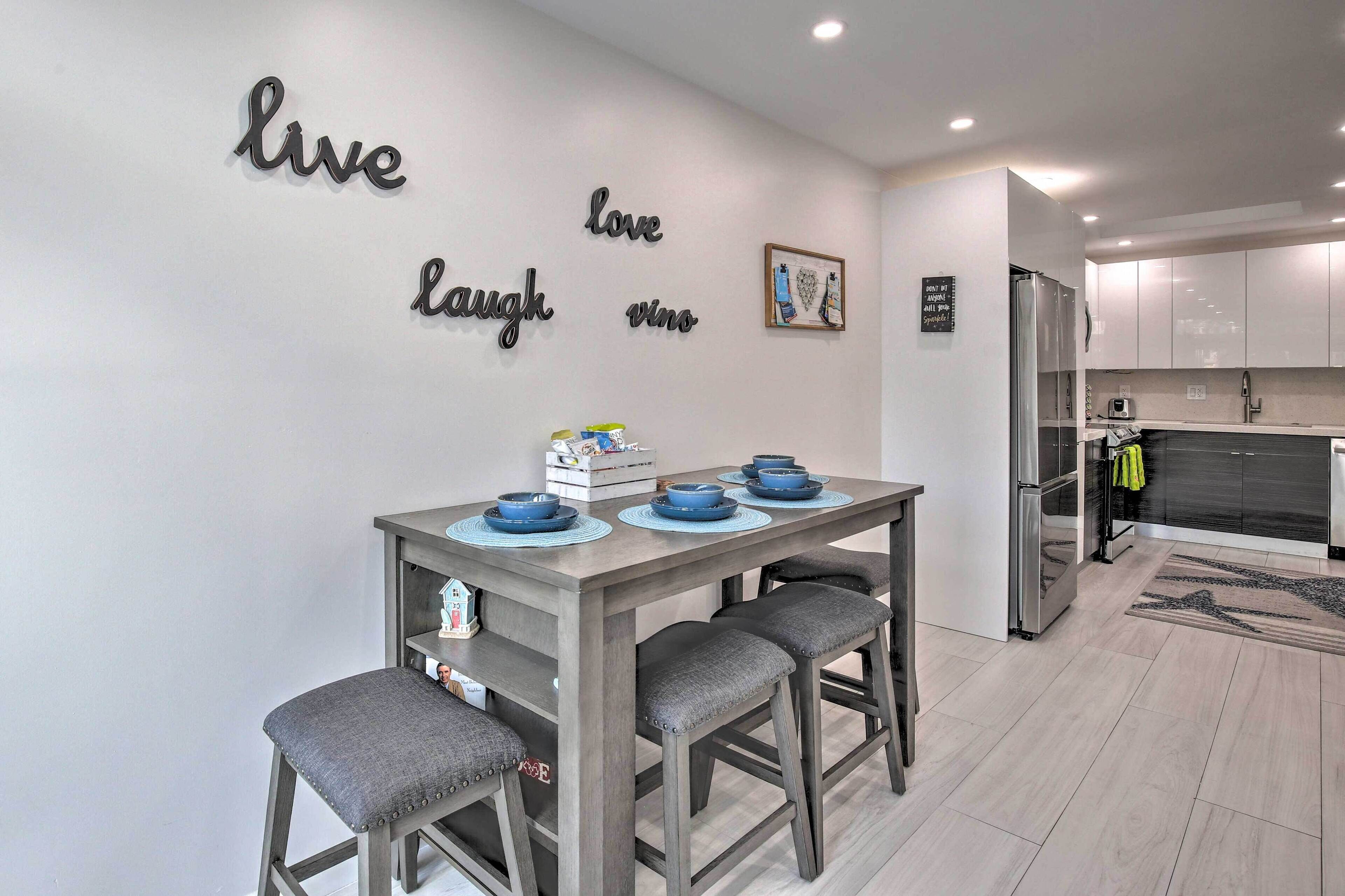 A modern kitchen with a dining table set for four, a refrigerator, and a kitchen island.