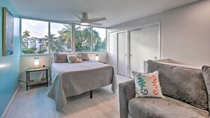 Un dormitorio con cama, mesita de noche, sofá y ventilador de techo.