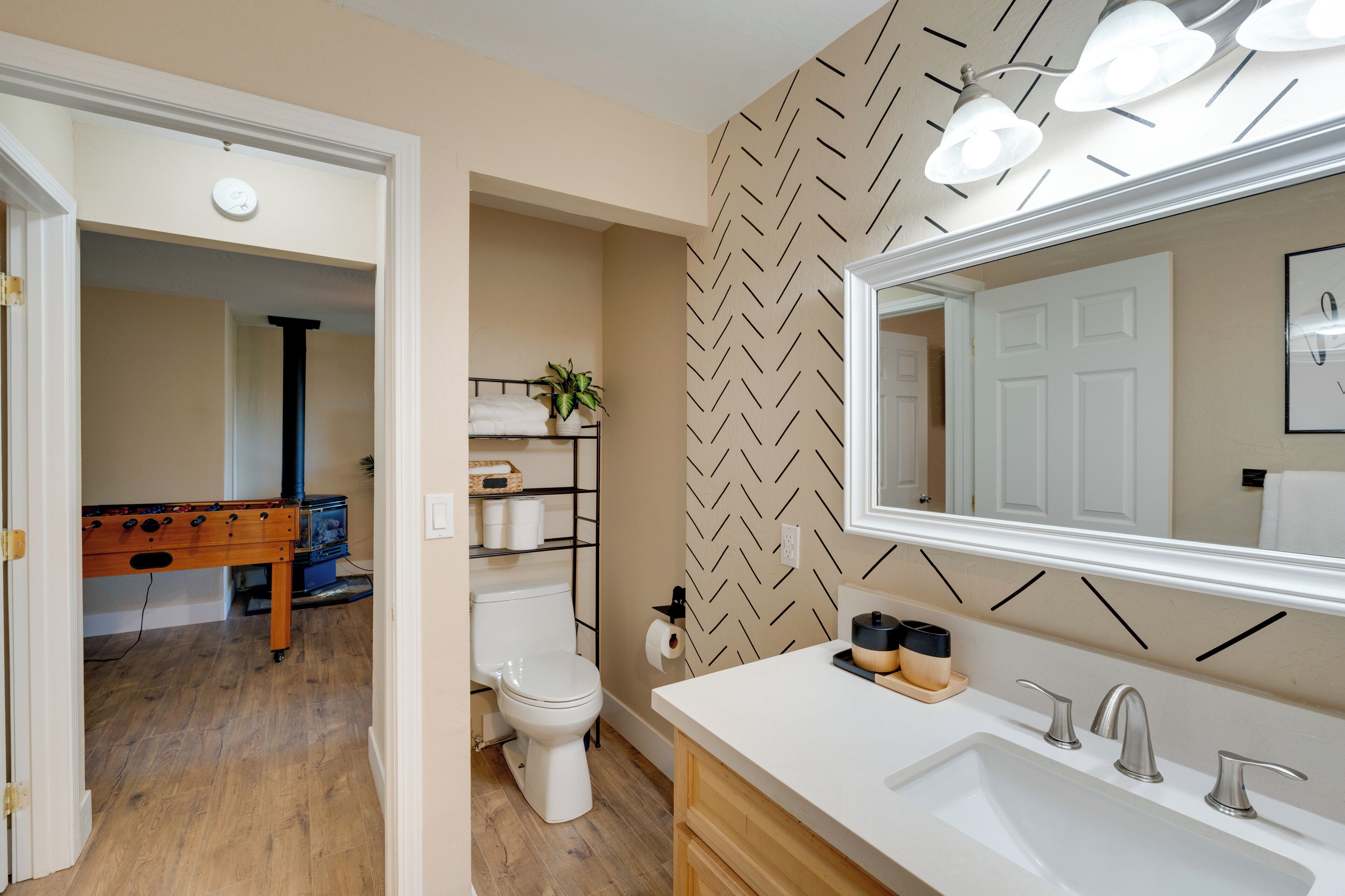 A bathroom with a white sink, mirror, and a herringbone-patterned wall.