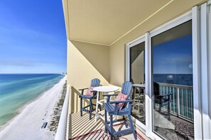 A balcony with a view of the beach, two chairs, a table, and a window. - Oceanfront Panama City Beach Condo w/ Pool Access! (Panama City Beach)