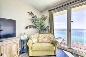 A living room with a sofa, a television, a small table, and a potted plant. - Oceanfront Panama City Beach Condo w/ Pool Access! (Panama City Beach)