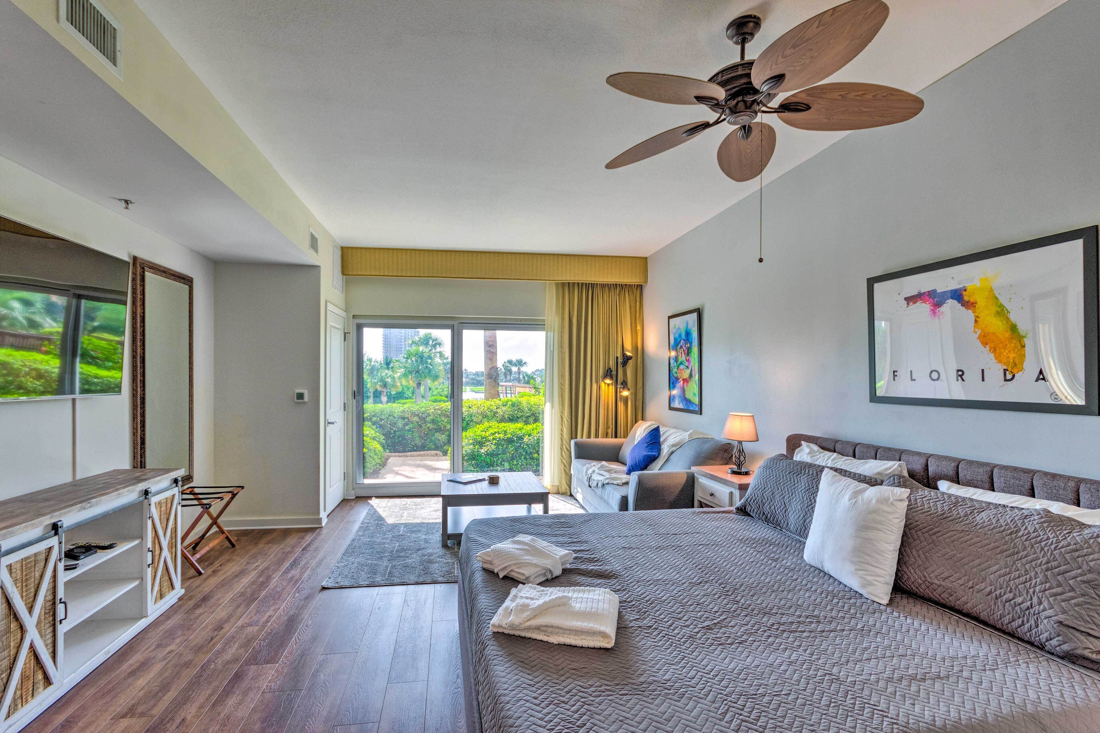 A hotel room with a bed, a desk, a chair, and a view of the outdoors.