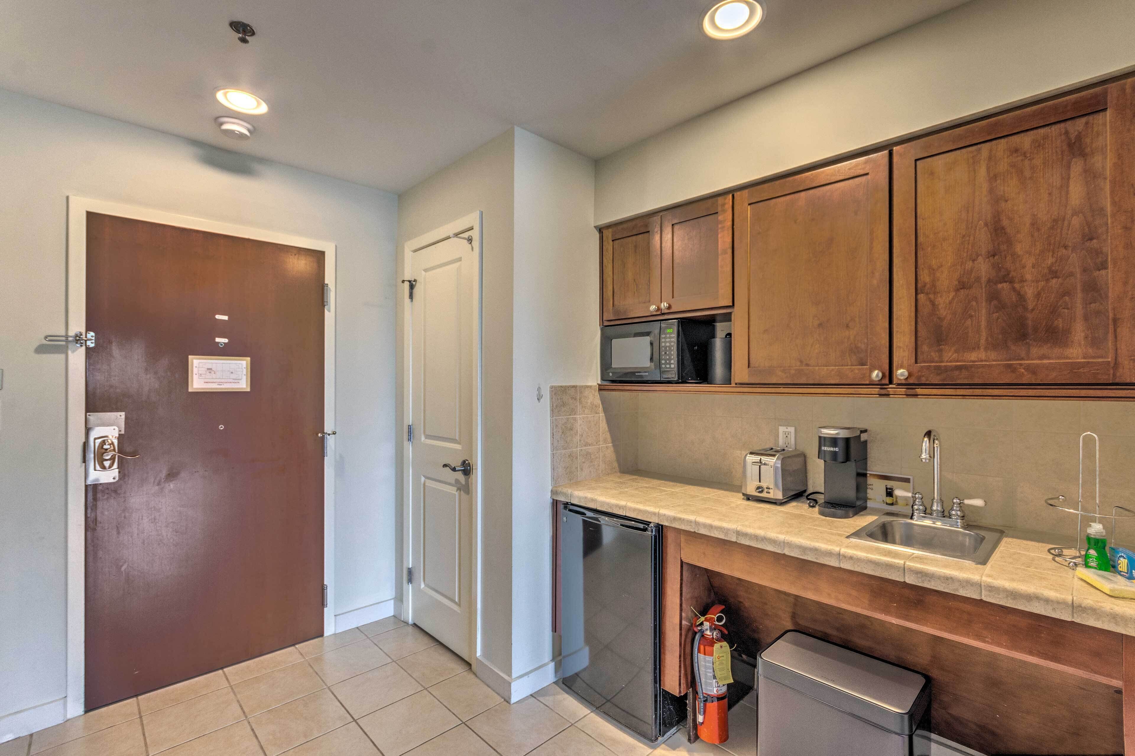 A compact kitchen with a microwave, toaster, and sink.