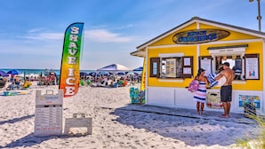 Um quiosque à beira-mar chamado 'Beach Concierge', com um cardápio e um aviso de 'Não Aceitamos Dinheiro'.