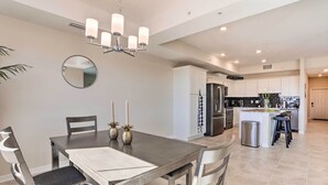 A modern kitchen with white cabinets, a stainless steel refrigerator, and a central island with stools. - 6 Mi to Disney: Resort Hideaway w/ Pool Access! (Kissimmee)