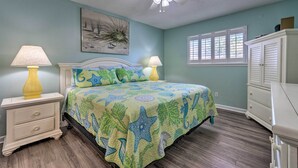 A bedroom with a bed, nightstands, a ceiling fan, a window, and a dresser.
