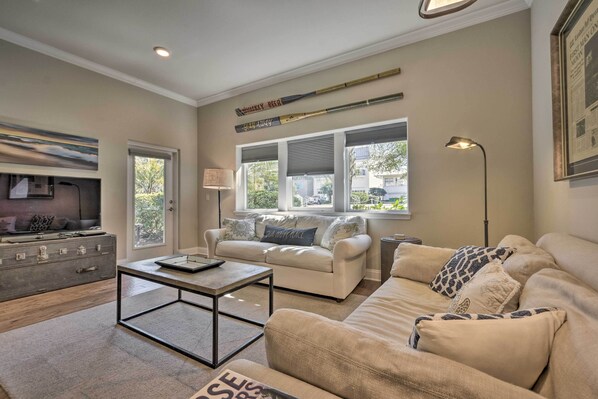 A living room with a sofa, a coffee table, a lamp, and a baseball bat on the wall.