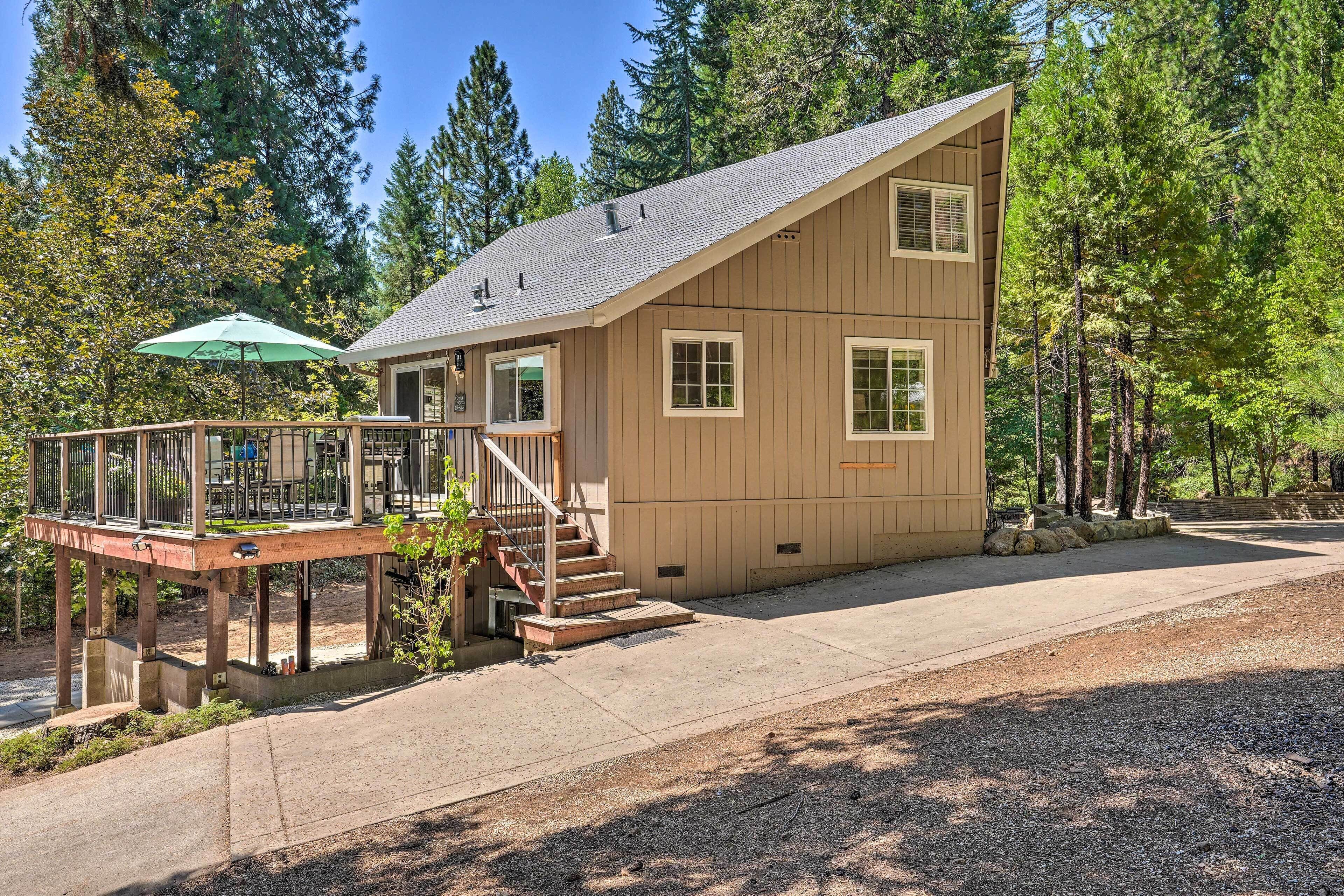 A two-story wooden cabin with a deck, a staircase, and a large window.