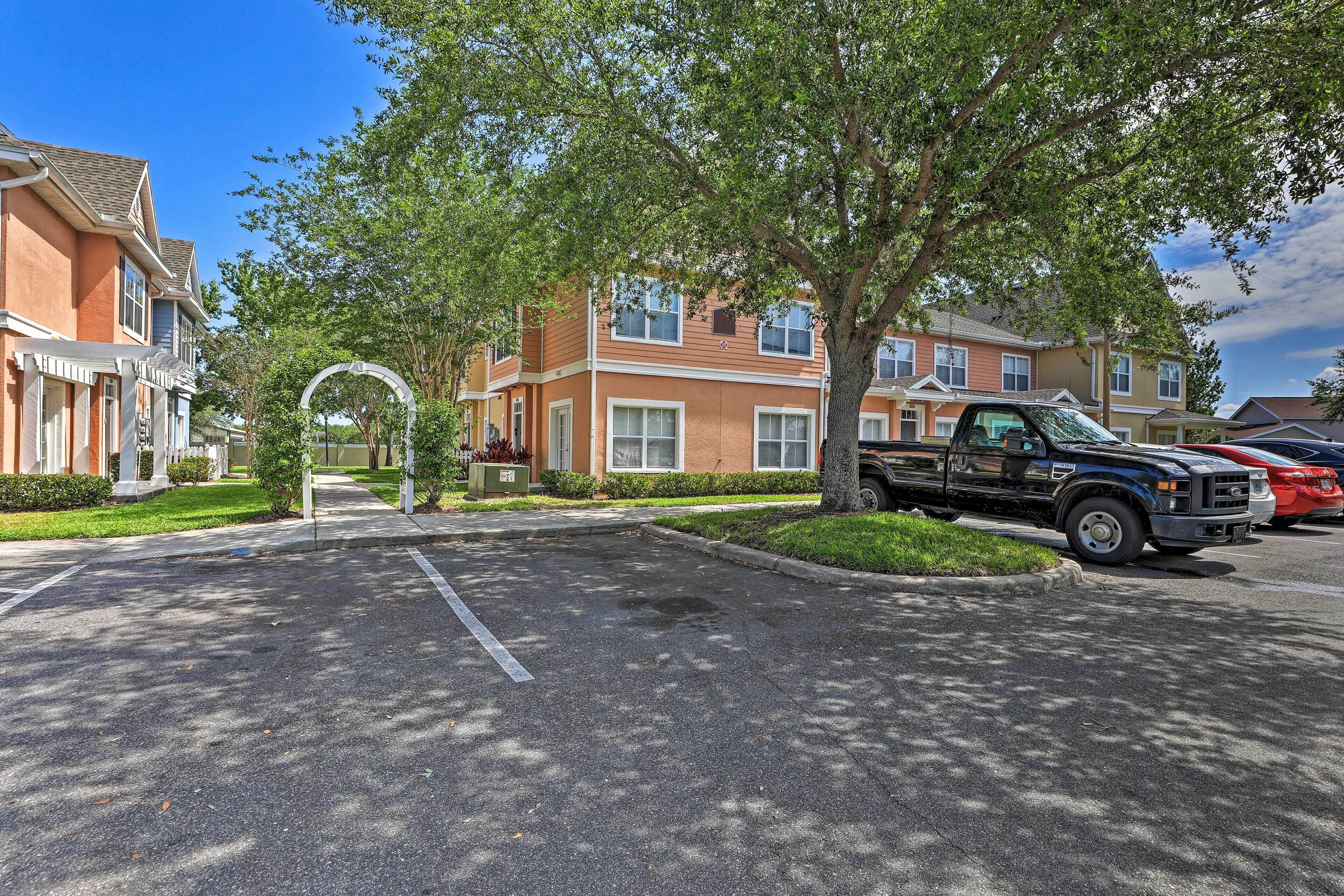 A residential street with houses, a parking lot, and a tree-lined driveway.