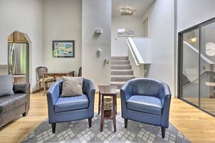 Una sala de estar moderna con dos sofás de cuero azul, una mesa de comedor de madera y una escalera que sube a un nivel superior.