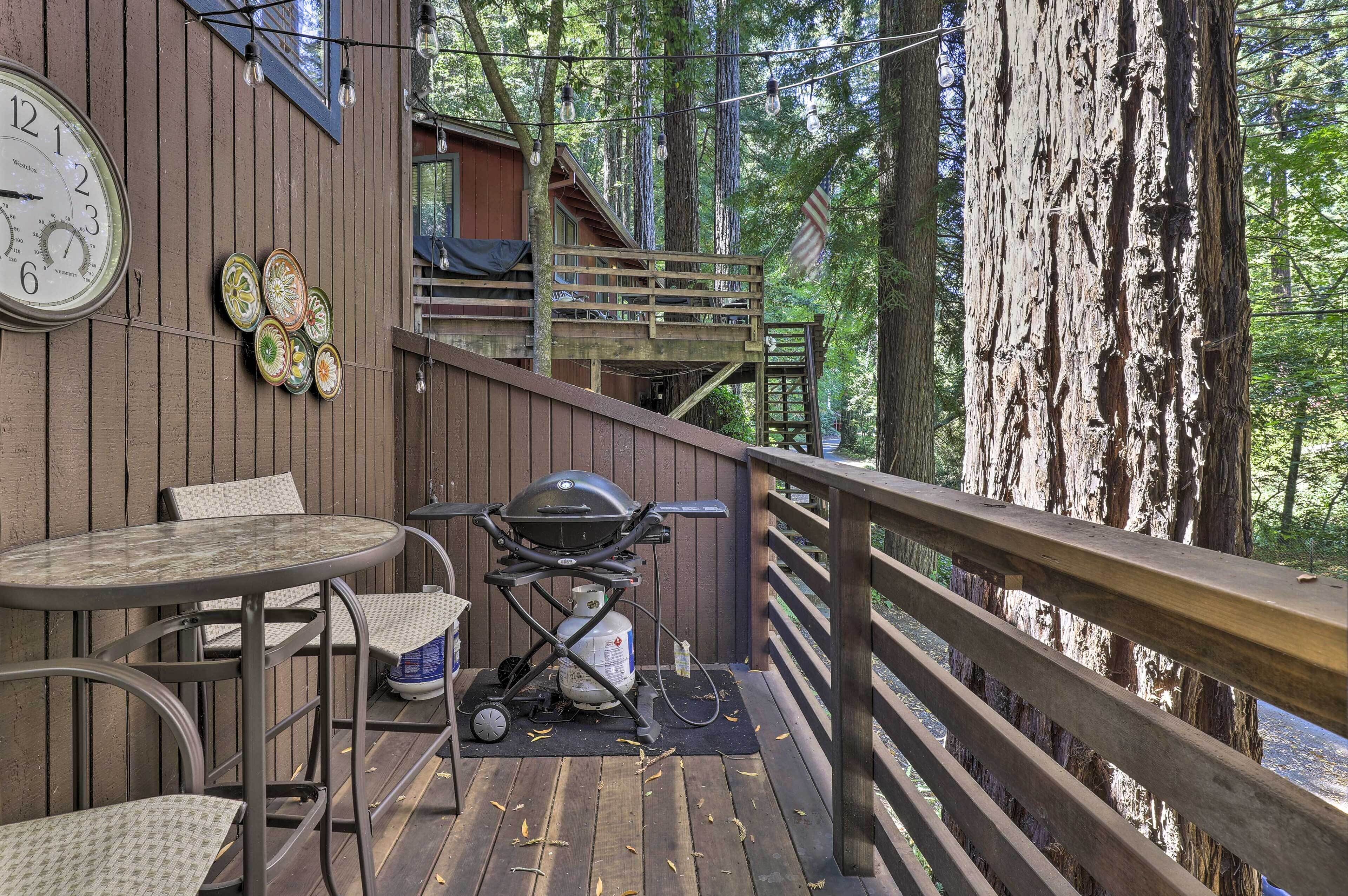Una terraza de madera con una parrilla, sillas y un reloj.