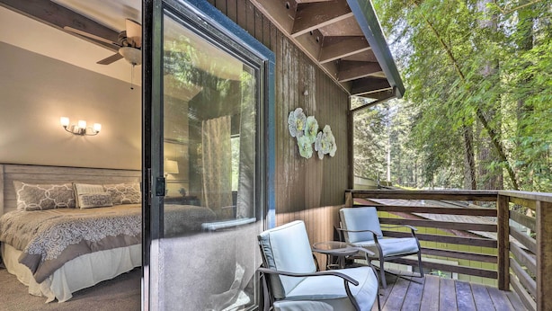 A bedroom with a bed, a chair, and a table on a wooden deck. - Tranquil Guerneville Home w/ Redwood Views (Guerneville)