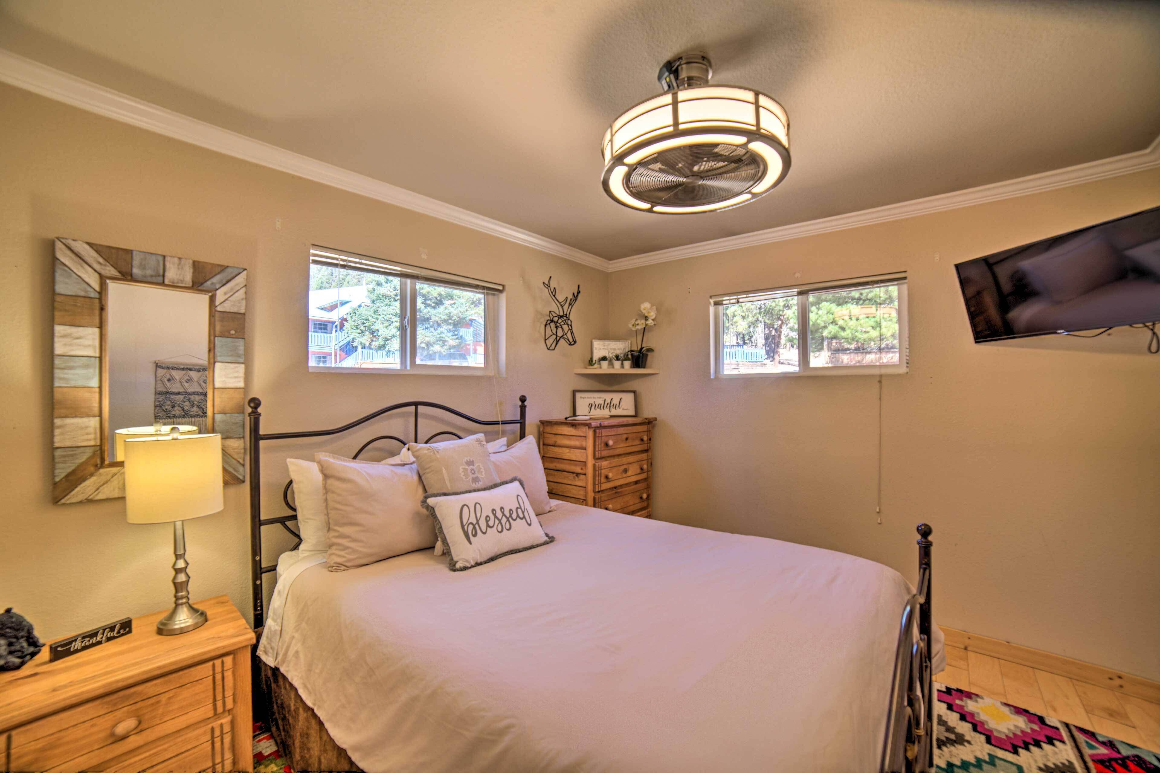 A bedroom with a bed, bedside table, lamp, dresser, and a ceiling fan.