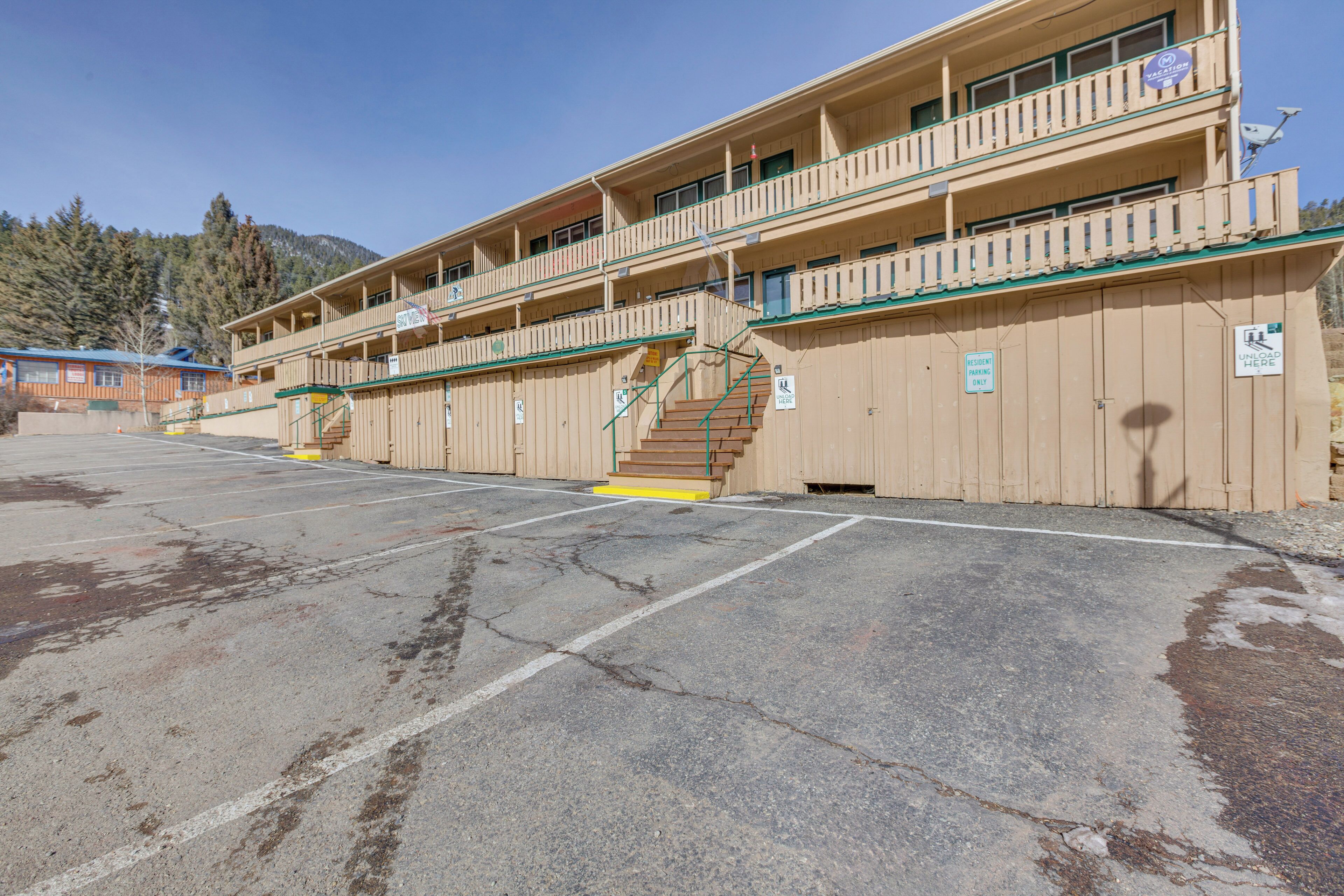 A multi-story building with a balcony on the upper floor, a staircase leading to the upper level, and a parking lot in front.