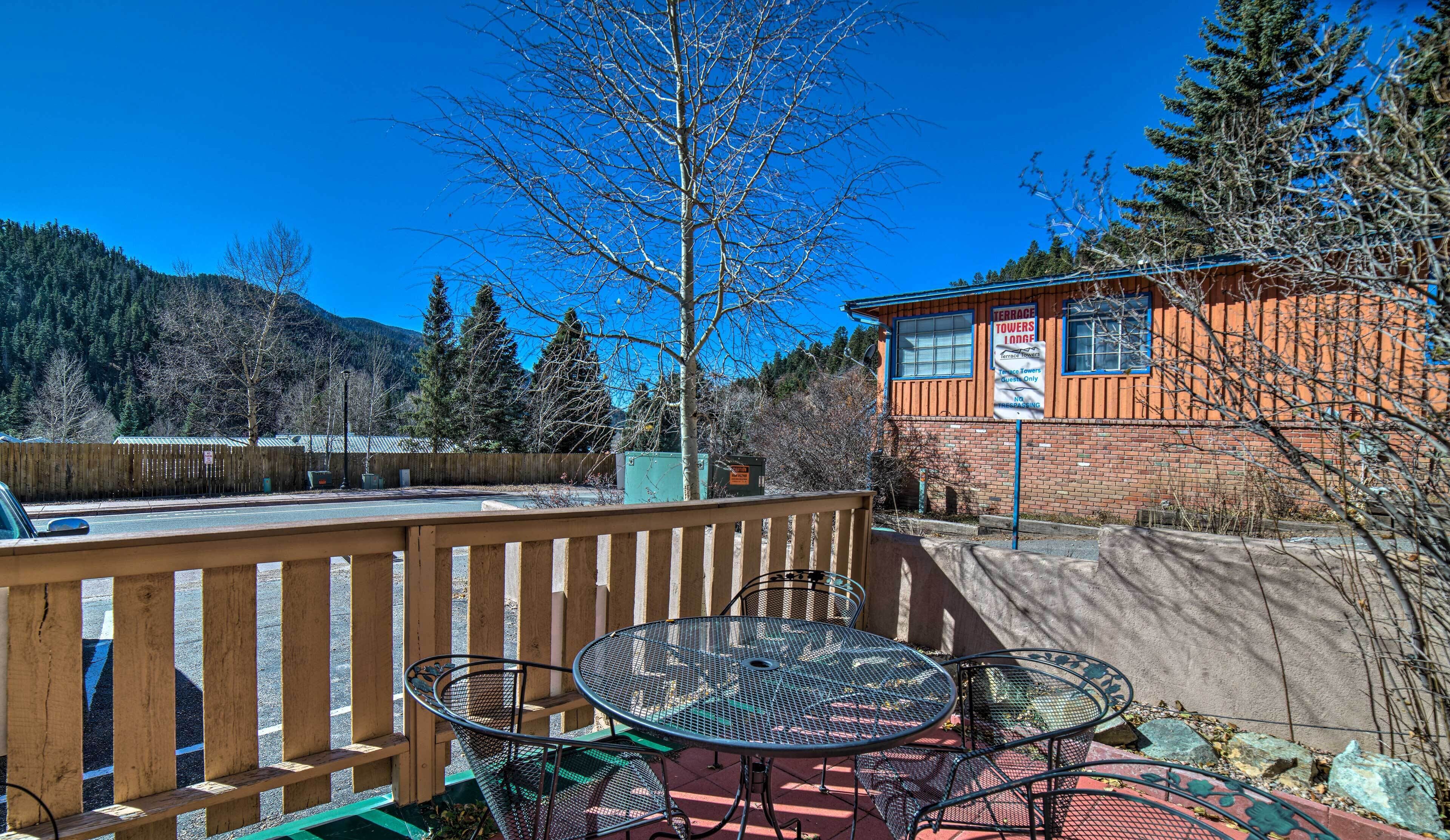 A terrace with metal tables and chairs, a wooden fence, and a building with a sign for Terrace Towers Lodge.