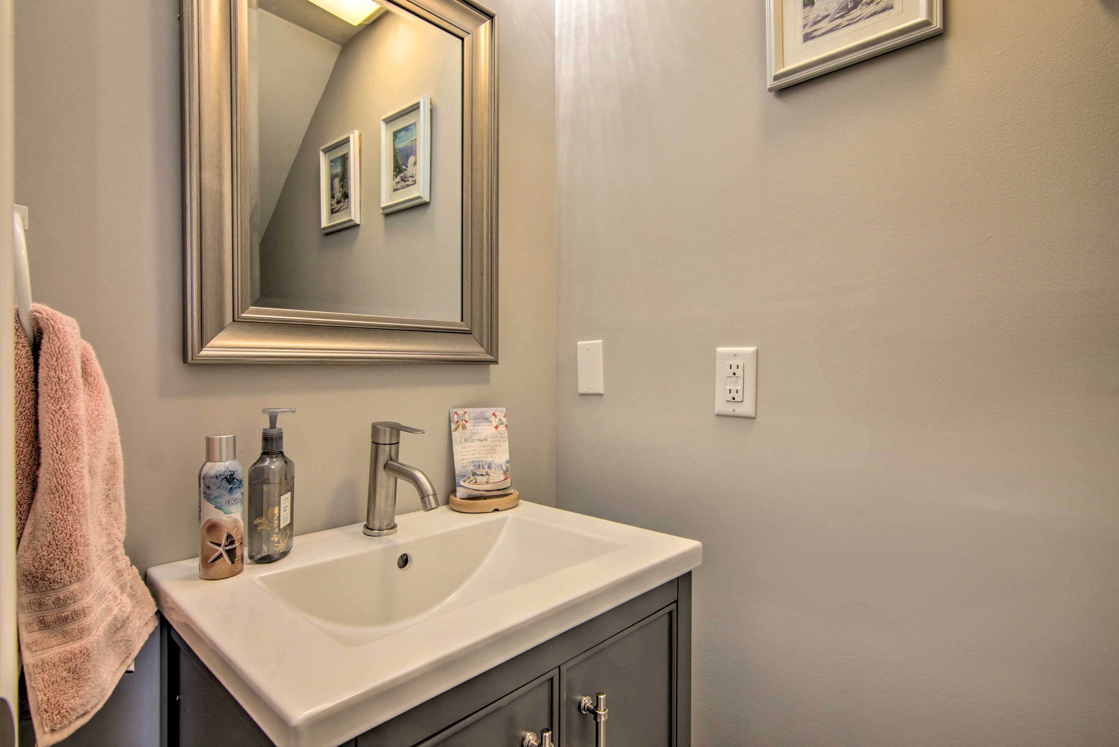 A bathroom with a white sink, a large mirror, and a towel hanging on the wall.