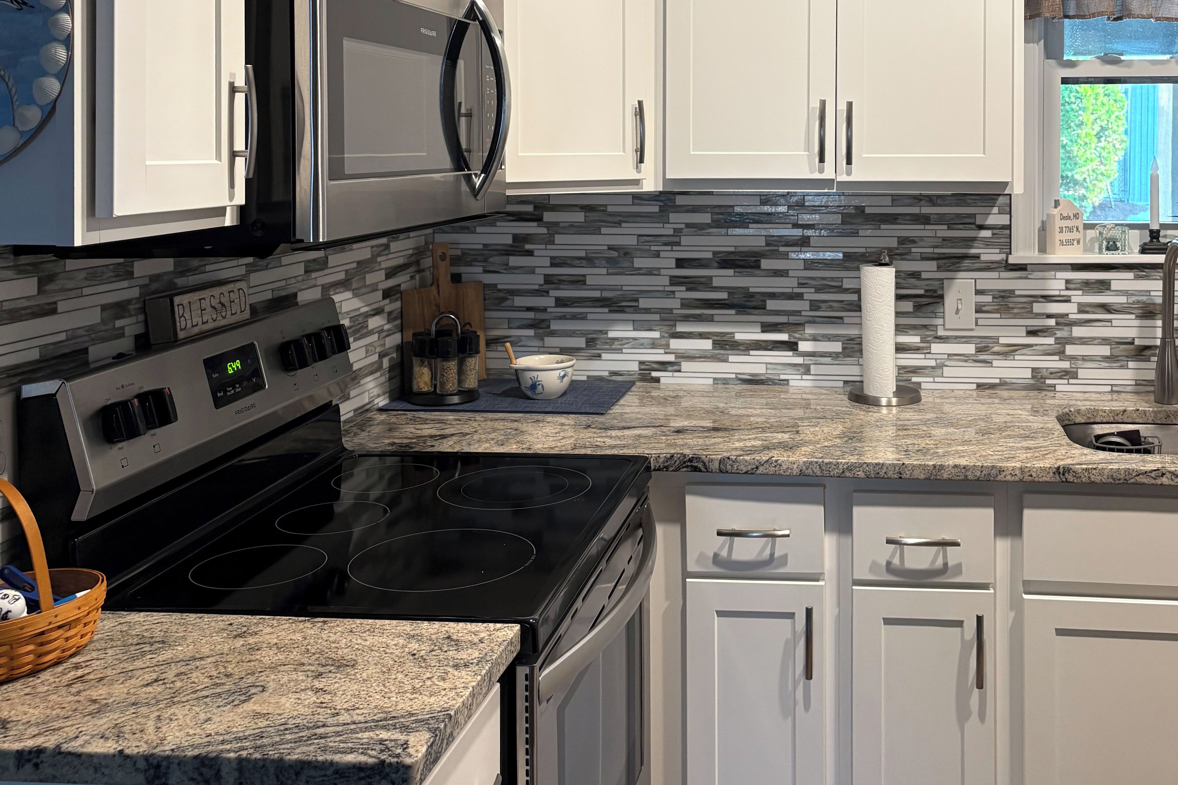 Una cocina moderna con armarios blancos, una estufa negra, un microondas y un salpicadero de azulejos.