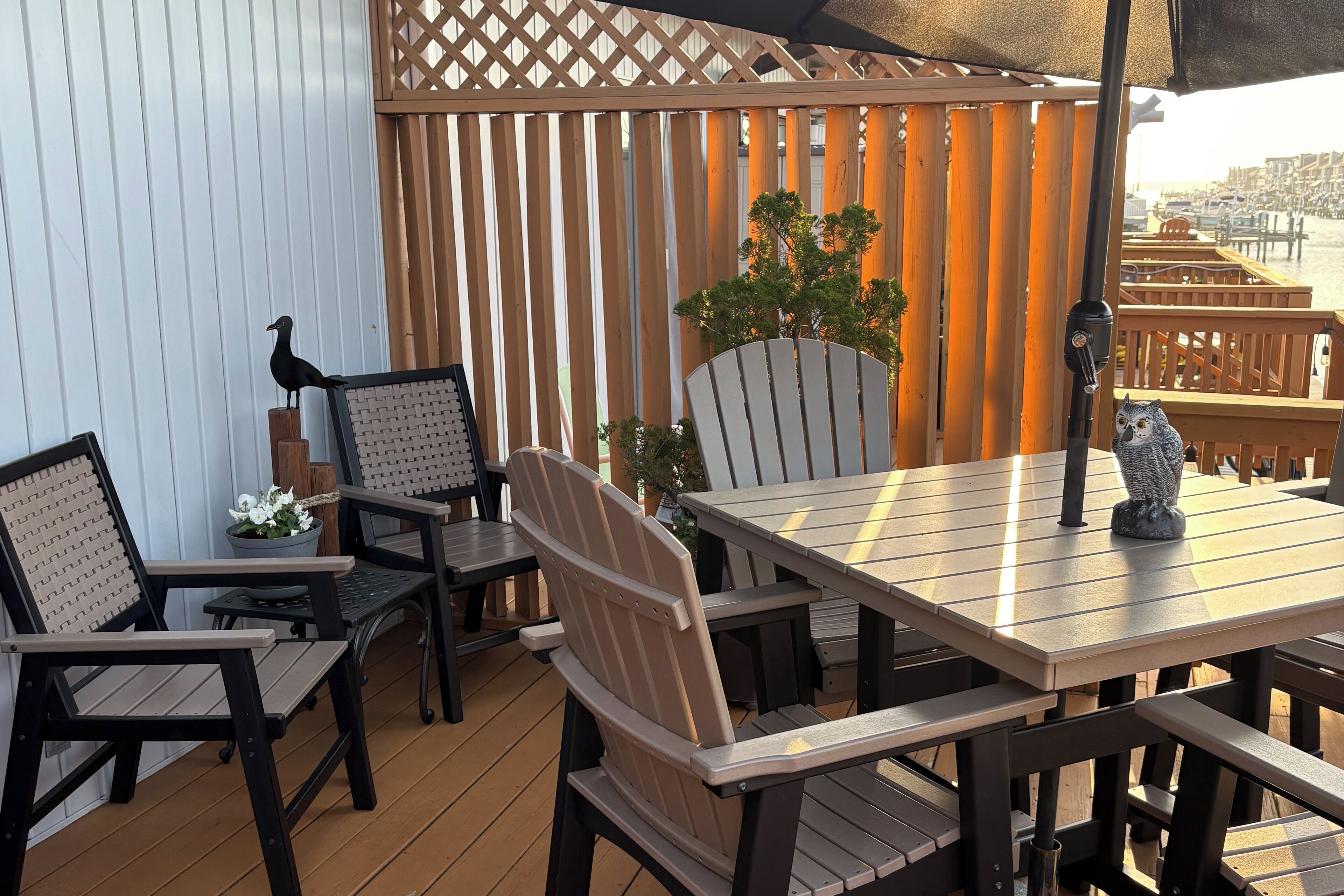 Eine Terrasse im Freien mit Holzmöbeln, einer Vogeldekoration und einem Blumentopf.