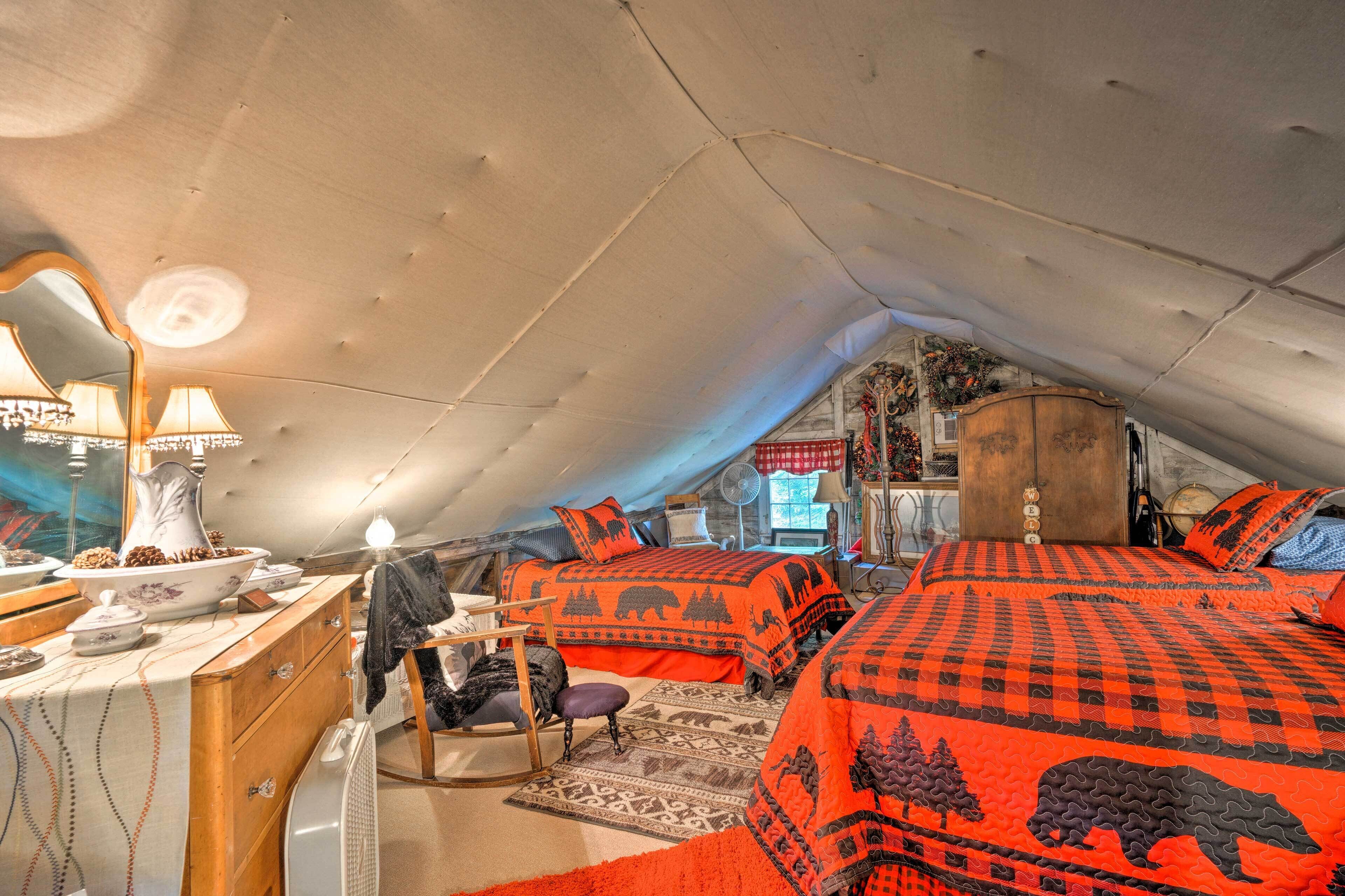 A cozy attic bedroom with two beds, a dresser, a chair, and a mirror.