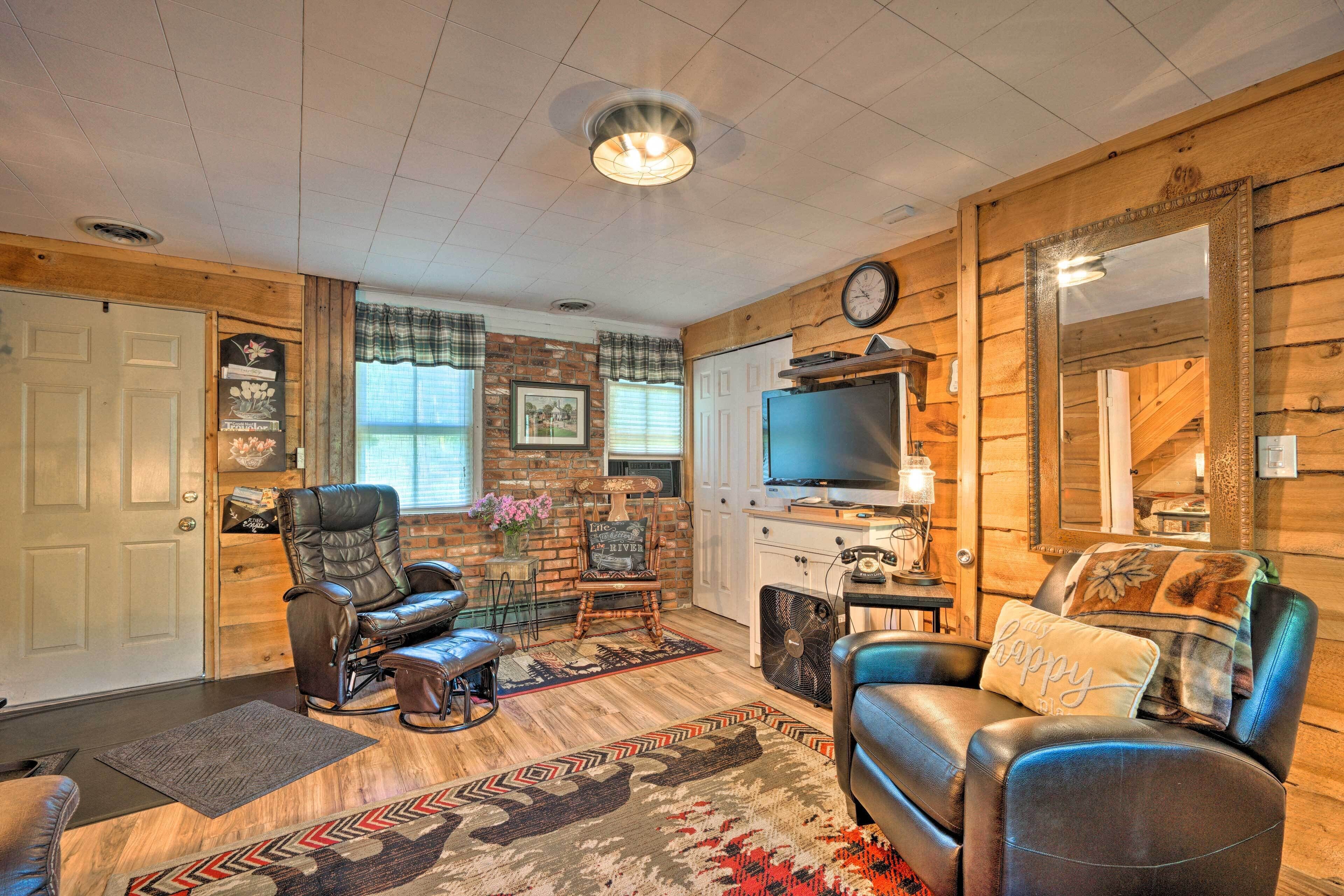 A cozy living room with a leather sofa, a recliner, a television, and a fireplace.