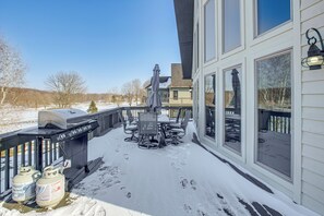 A covered outdoor patio with a grill, seating, and propane tanks.