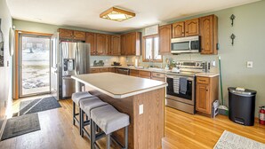 A modern kitchen with wooden cabinets, stainless steel appliances, and a large island with bar stools. - Apple Valley Home, Shared Golf Course On-site (Howard)
