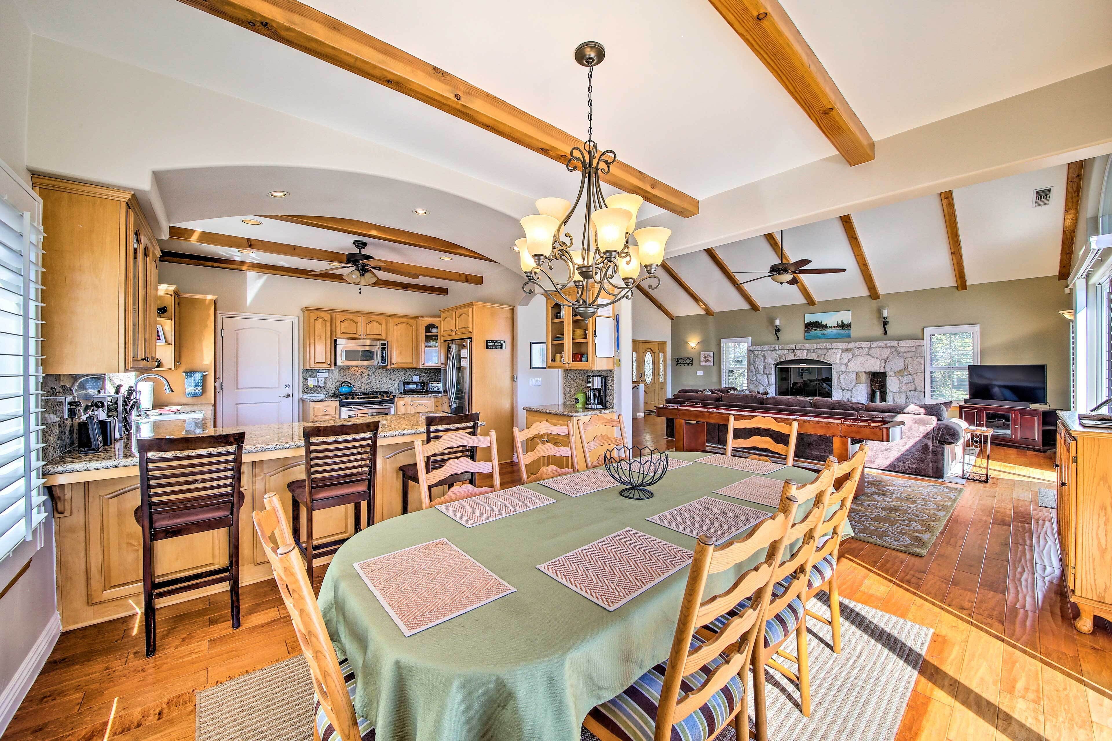 A spacious kitchen with wooden beams, a dining area with a table set for four, and a living area with a fireplace.