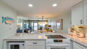 Cocina moderna con armarios blancos, microondas integrado, horno y una isla grande con estufa.