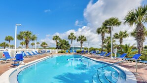 Una piscina con sillas de descanso azules y palmeras.