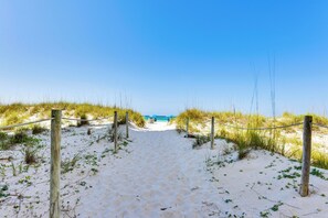 A sandy beach path leading to a beach with a clear blue sky. - Emerald Dreams Beach & Lakefront West PCB Condo (Panama City Beach)