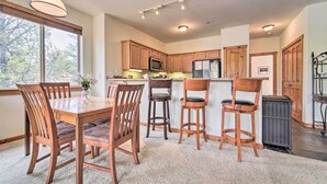 A modern kitchen with wooden cabinets, a central island, and a dining area with wooden chairs and a table. - 2 Mi to Donner Lake: Walkable Truckee Condo! (Truckee)