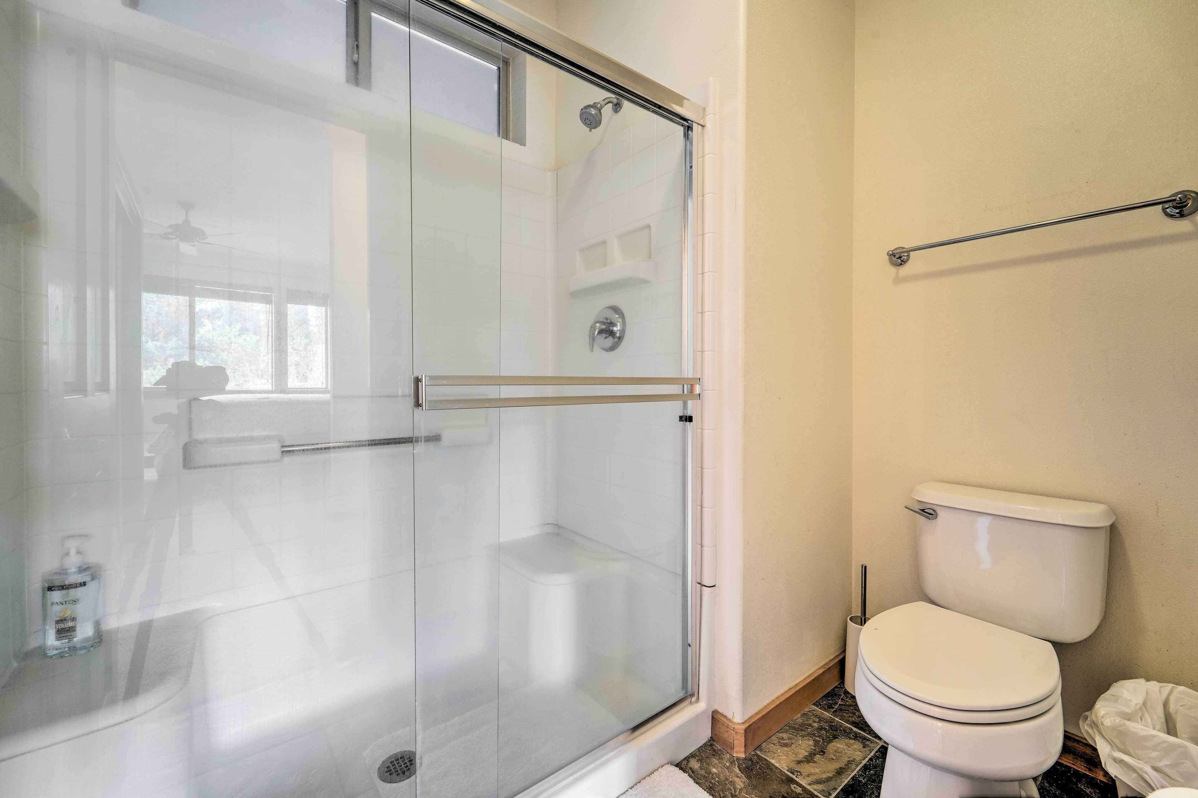 A bathroom with a glass-enclosed shower, a toilet, and a towel rack.