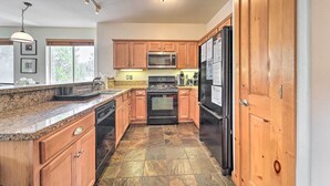 A kitchen with granite countertops, wooden cabinets, a stainless steel refrigerator, a microwave, and a stove. - 2 Mi to Donner Lake: Walkable Truckee Condo! (Truckee)