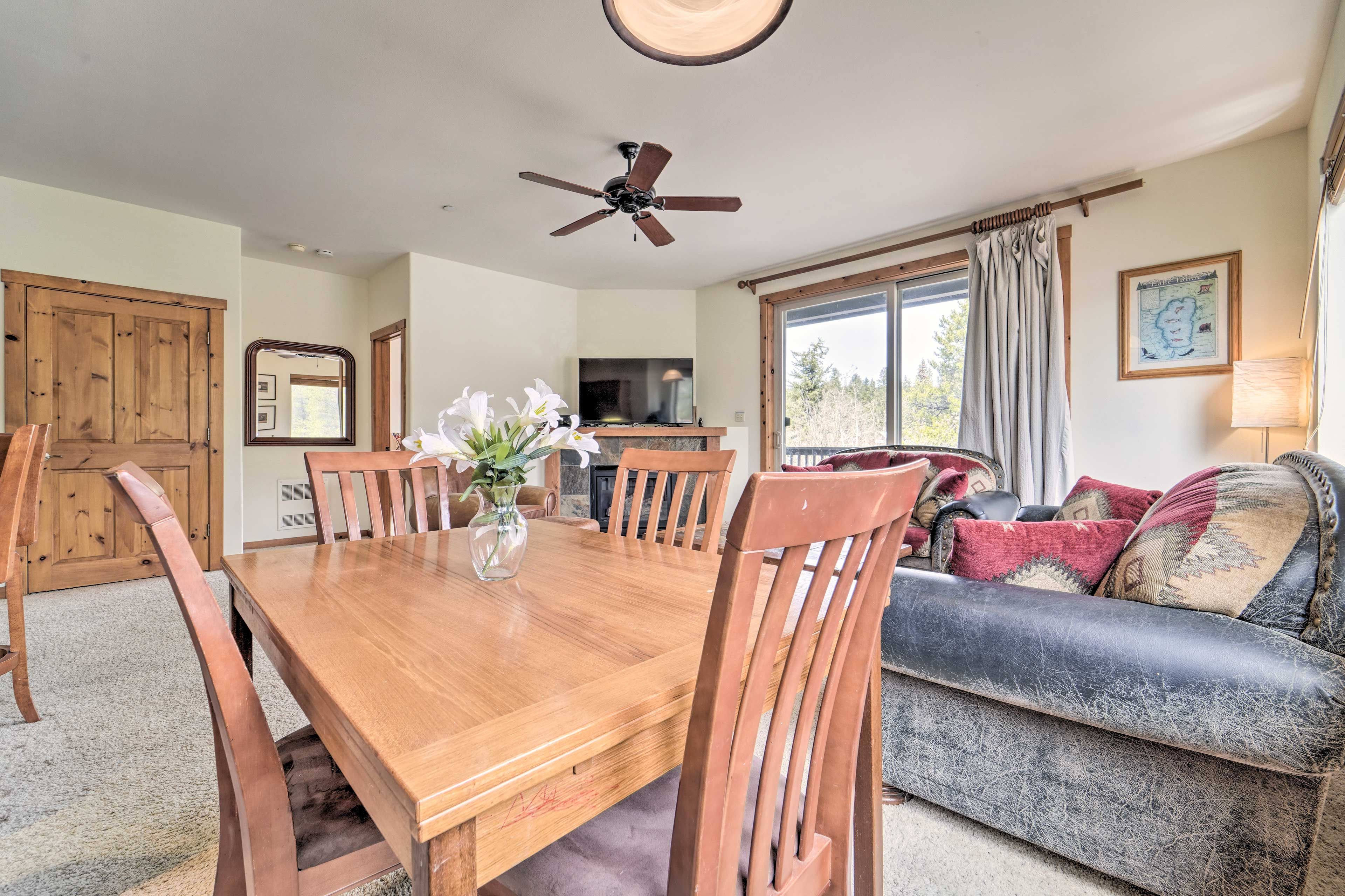 A dining area with a wooden table, chairs, a vase of flowers, and a ceiling fan.