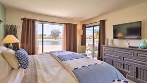 Ein Hotelzimmer mit einem großen Bett, einem Fernseher, einer Kommode und Blick auf einen Golfplatz.