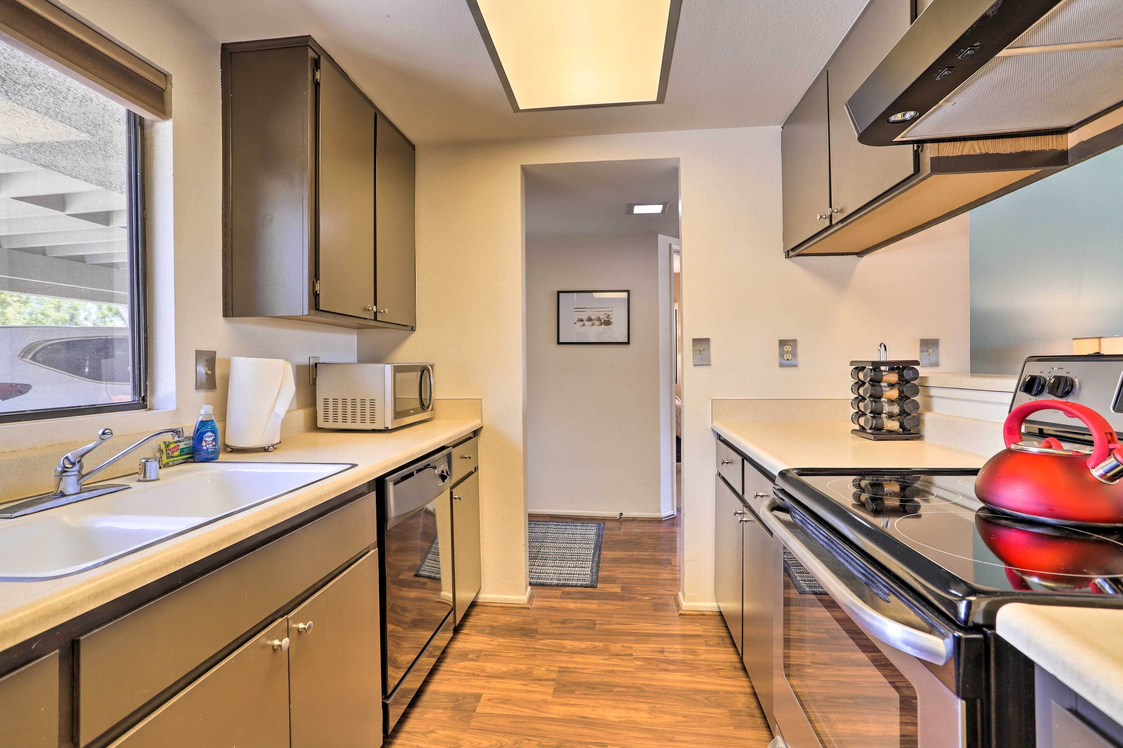 A modern kitchen with stainless steel appliances, a microwave, and a red kettle.