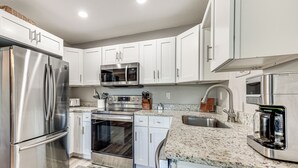 A modern kitchen with stainless steel appliances, white cabinetry, granite countertops, and a built-in oven. - Colorful Cottage 1 Mi to Historic District! (St. Augustine)