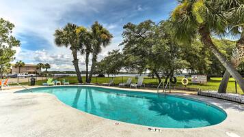 A swimming pool with lounge chairs and palm trees.