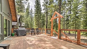 Une terrasse en bois avec des sièges extérieurs et une vue sur de grands arbres.