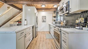 Une cuisine moderne avec des armoires blanches, une cuisinière en acier inoxydable et un plafond en bois.