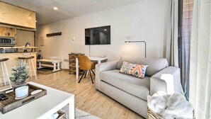 A modern living room with a grey sofa, a dining area with a wooden table, and a kitchen with a microwave. - Walk to Ski Resort: Tahoe Donner Studio w/ Balcony (Truckee)