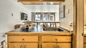 A kitchen with wooden cabinets, a stainless steel sink, and a window with curtains. - Walk to Ski Resort: Tahoe Donner Studio w/ Balcony (Truckee)