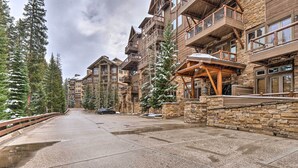 Un bâtiment à plusieurs étages, de style chalet, avec une architecture en pierre et en bois, doté de balcons et d’une galerie couverte.