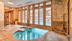 Un espace piscine avec vue sur l’extérieur, un banc en bois et un porte-manteau.