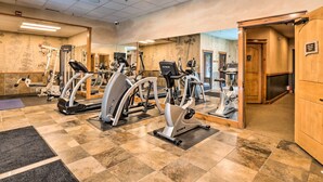 Une salle de sport équipée de plusieurs appareils de cardio, d’un miroir, ainsi que d’une piscine et d’un sauna.