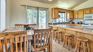 A kitchen with wooden cabinets, a central island with stools, and a dining area with a table and chairs.